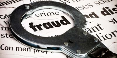 Handcuffs over the word "fraud" written on a newspaper