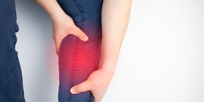 A man holds an aching calf muscle as the area is highlighted in red.